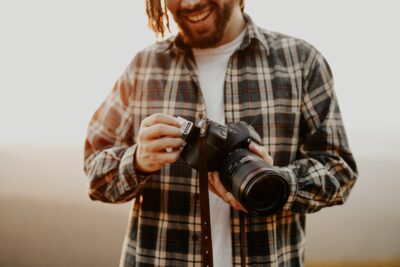 Partial face shot of smiling young man loading a memory card into a DSLR camera