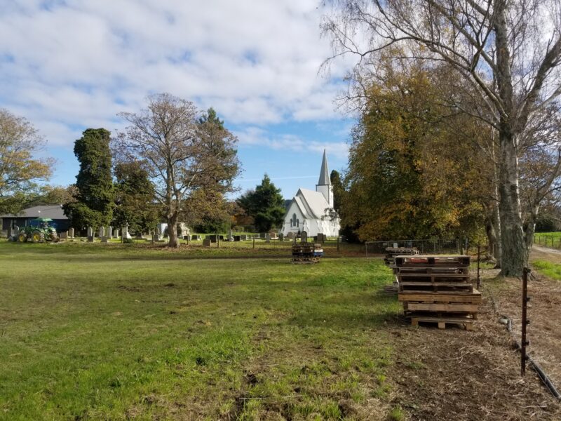 Empty paddock with church in the background and pallets stacked on one side