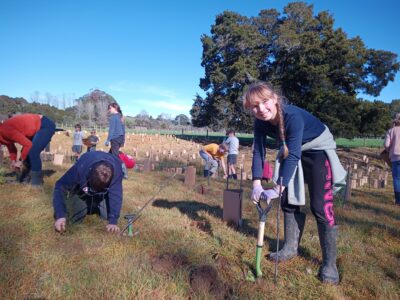 A young female student of Upper Moutere School digging holes for planting native plants at Beuke Bush